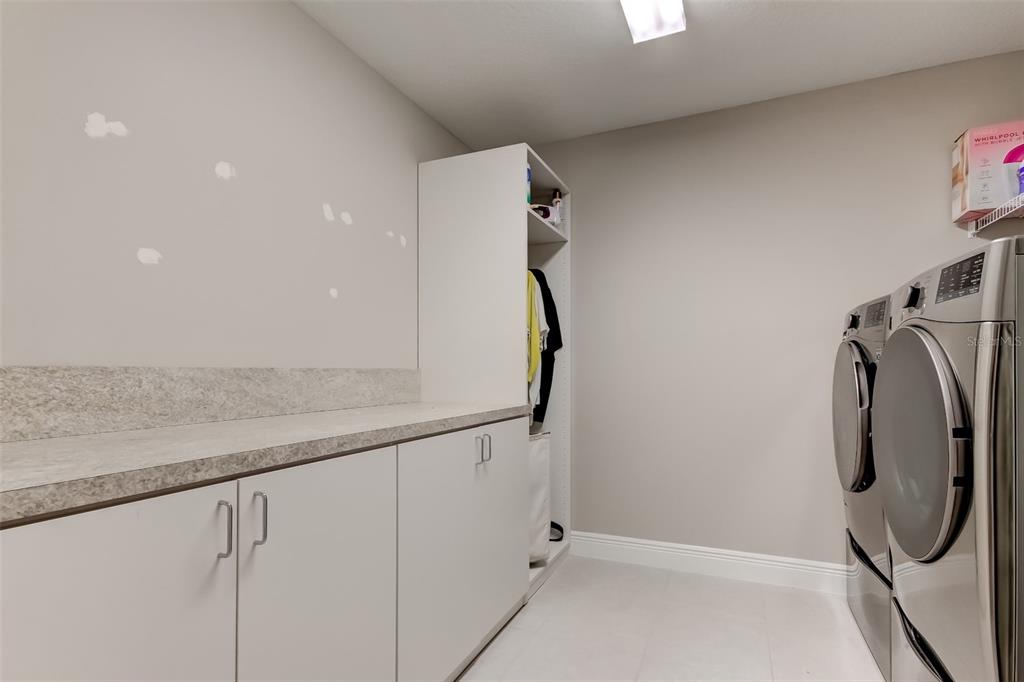 A laundry room features white cabinets, a stone countertop, and a side-by-side washer and dryer — 13118 JETER CREEK DRIVE, RIVERVIEW, FL