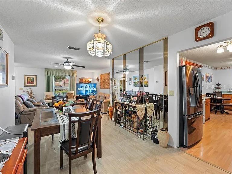 A dining area with a wooden table and chairs sits adjacent to a mirrored wall — 11404 STANSBERRY DRIVE, PORT RICHEY, FL
