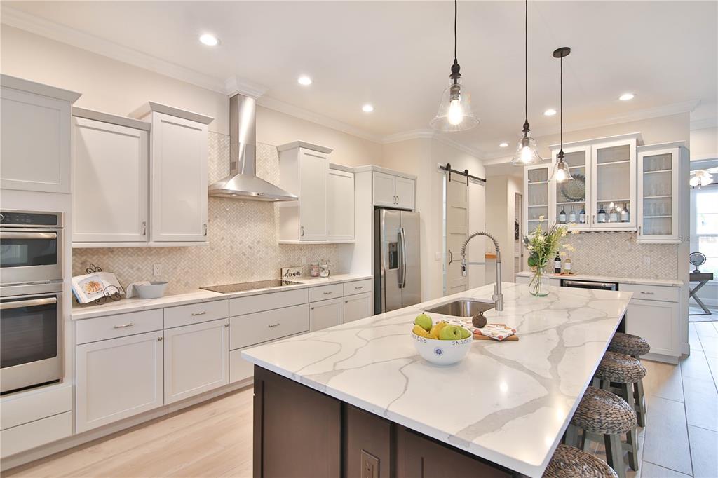 A kitchen features a large marble-topped island, dark cabinetry, and white upper cabinets — 7808 34TH COURT E, SARASOTA, FL
