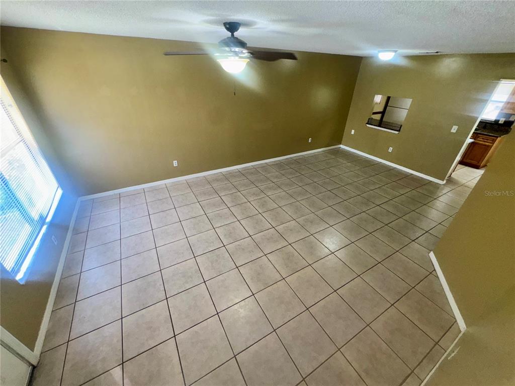 An empty room features tan walls, a ceiling fan, and light-colored square floor tiles — 1605 SHADY RIDGE COURT, ORLANDO, FL