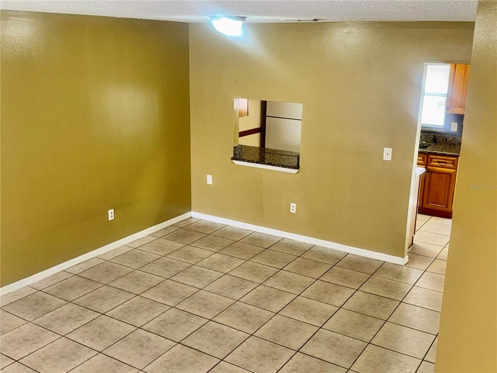 A dining room with tan walls, tile flooring, and a pass-through window to the kitchen — 1605 SHADY RIDGE COURT, ORLANDO, FL