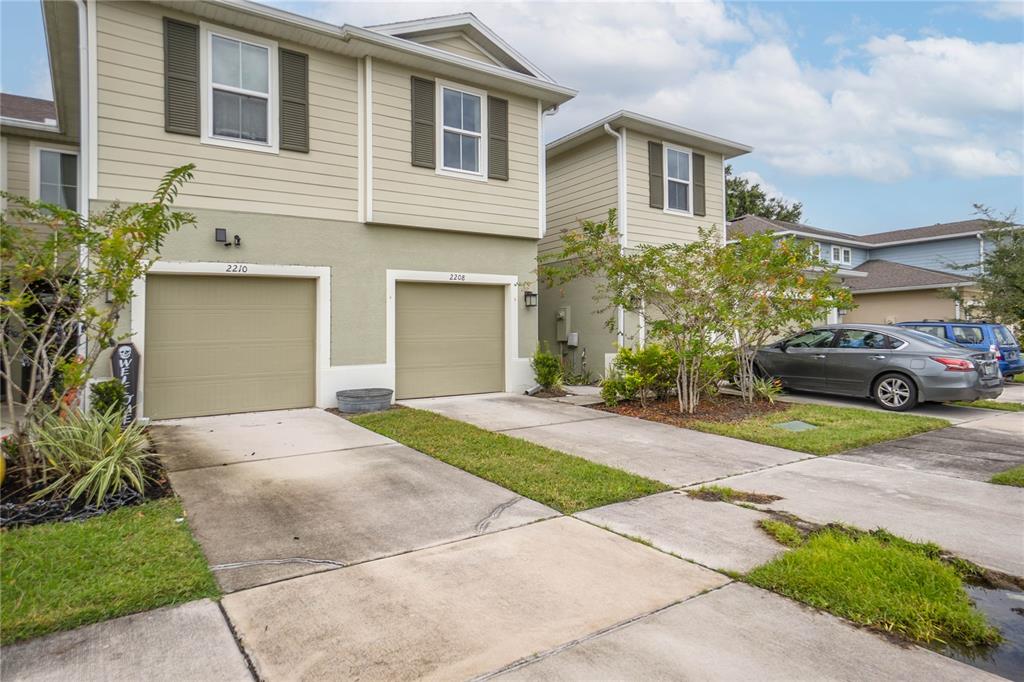 The exterior of two attached townhomes features beige siding, concrete driveways, and two-car garages — 2208 LACEFLOWER DRIVE, BRANDON, FL