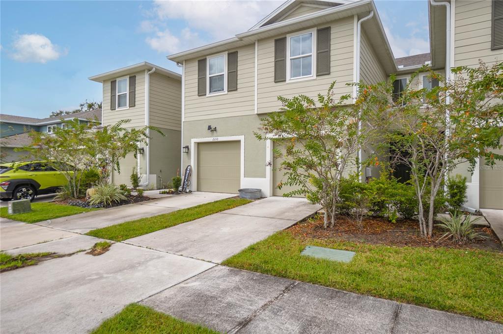 A two-story townhouse with light green siding, a single-car garage, and a concrete driveway — 2208 LACEFLOWER DRIVE, BRANDON, FL