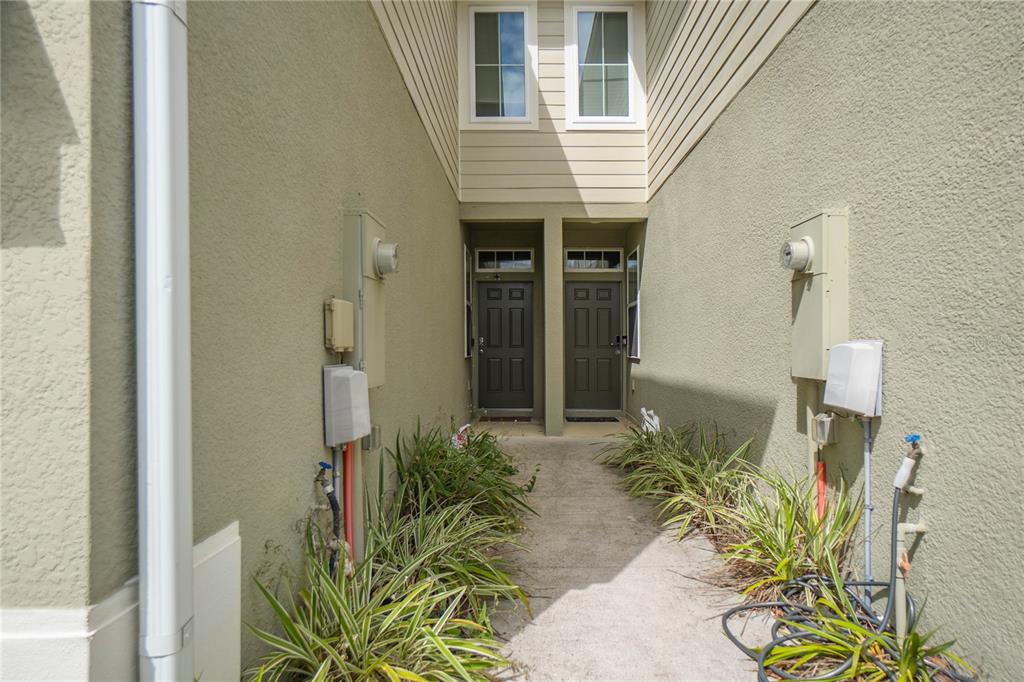 A concrete walkway leads to two dark front doors between two beige stucco walls — 2208 LACEFLOWER DRIVE, BRANDON, FL