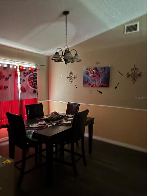 A dining room features a dark wood table, four chairs, and a chandelier — 116 SPOONBILL COURT, KISSIMMEE, FL