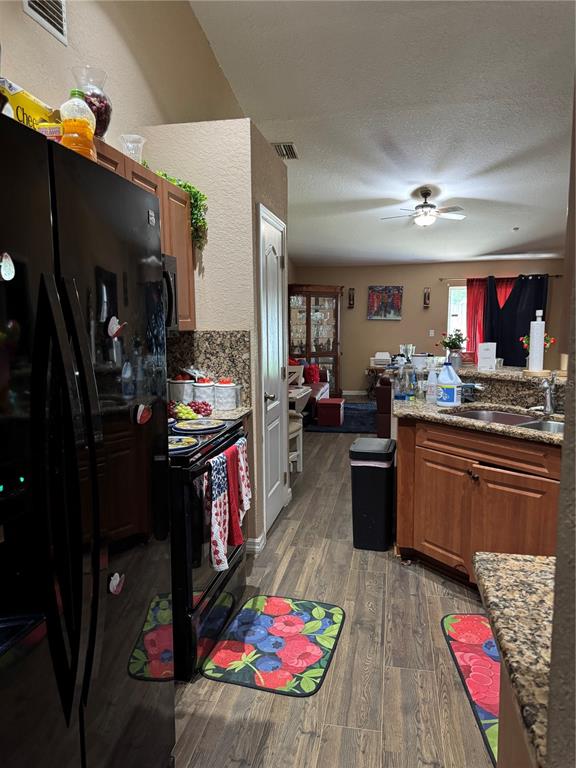 A kitchen with wood cabinets, granite countertops, and stainless steel appliances opens into a living area — 116 SPOONBILL COURT, KISSIMMEE, FL