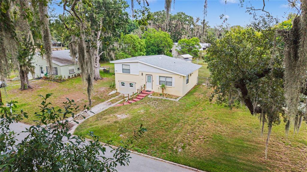 An elevated view of a yellow single-story house with a white roof and front steps — 305 CORDOVA ROAD, AUBURNDALE, FL