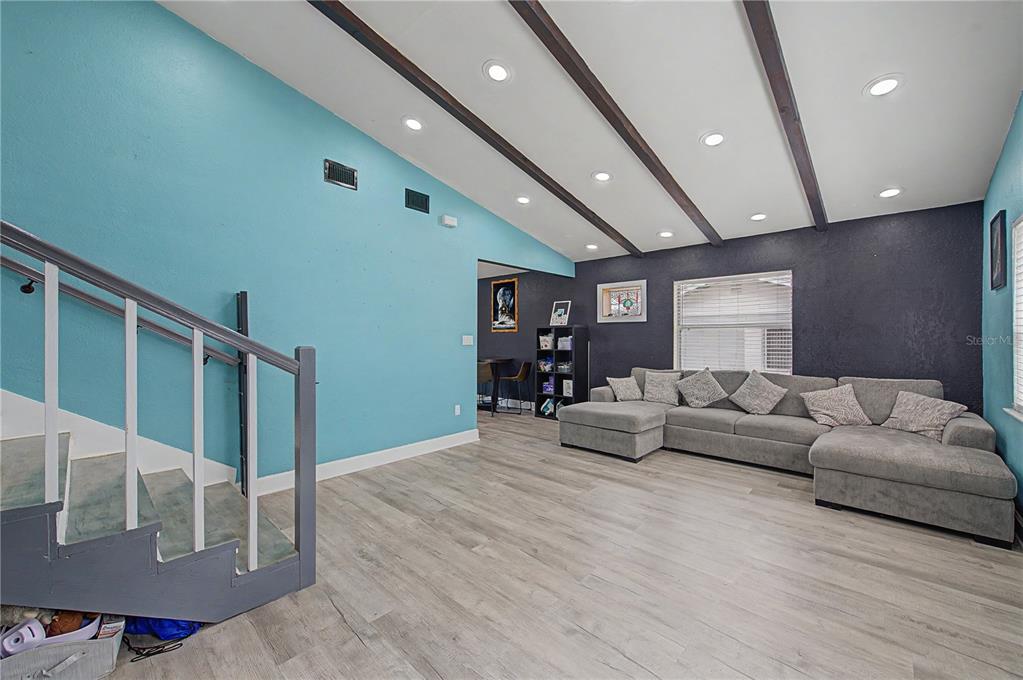 A living room features light blue and dark walls, wood-look flooring, and exposed ceiling beams — 305 CORDOVA ROAD, AUBURNDALE, FL