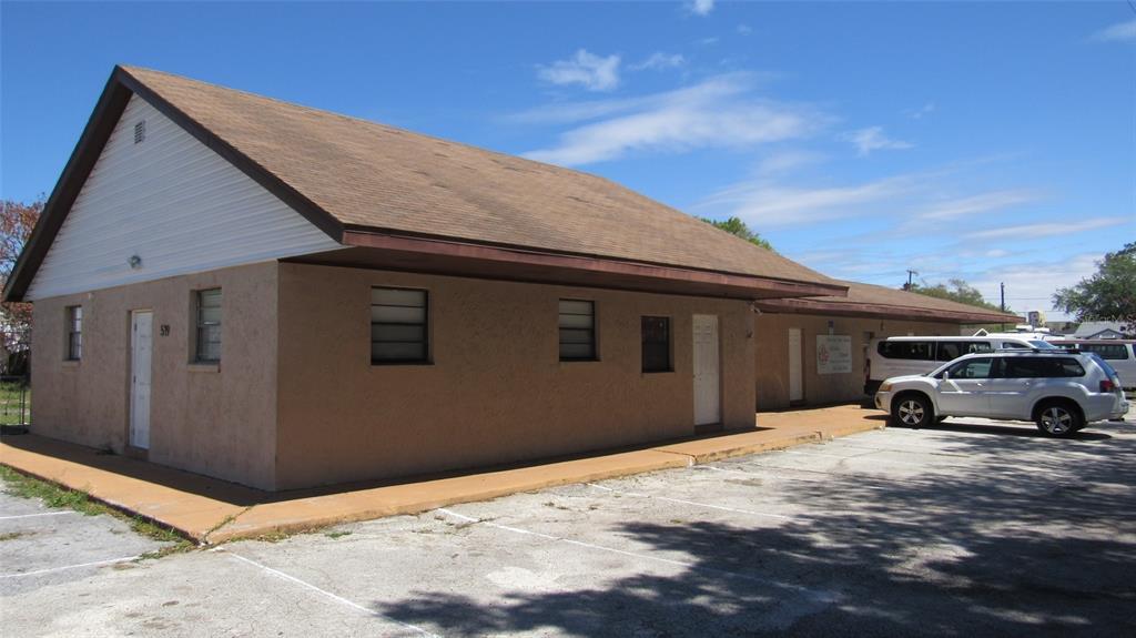 A single-story commercial building with a tan stucco exterior and a brown shingled roof — 0 MELTON AVENUE, AUBURNDALE, FL
