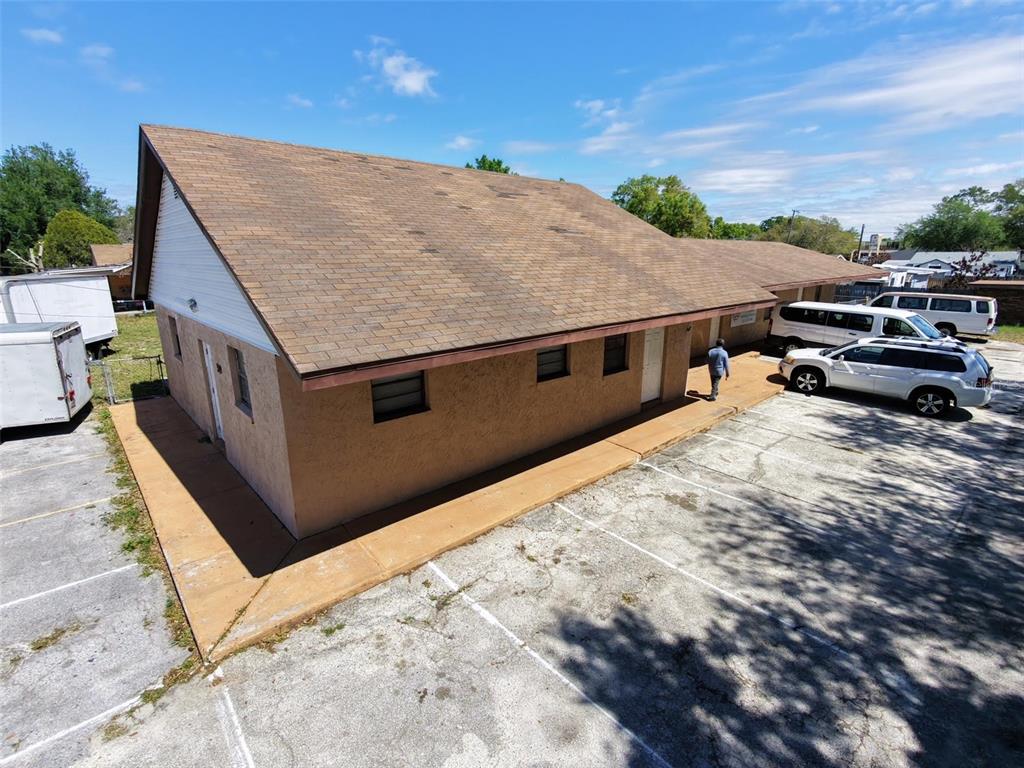 An exterior view of a single-story commercial building with a brown shingled roof and parking — 0 MELTON AVENUE, AUBURNDALE, FL