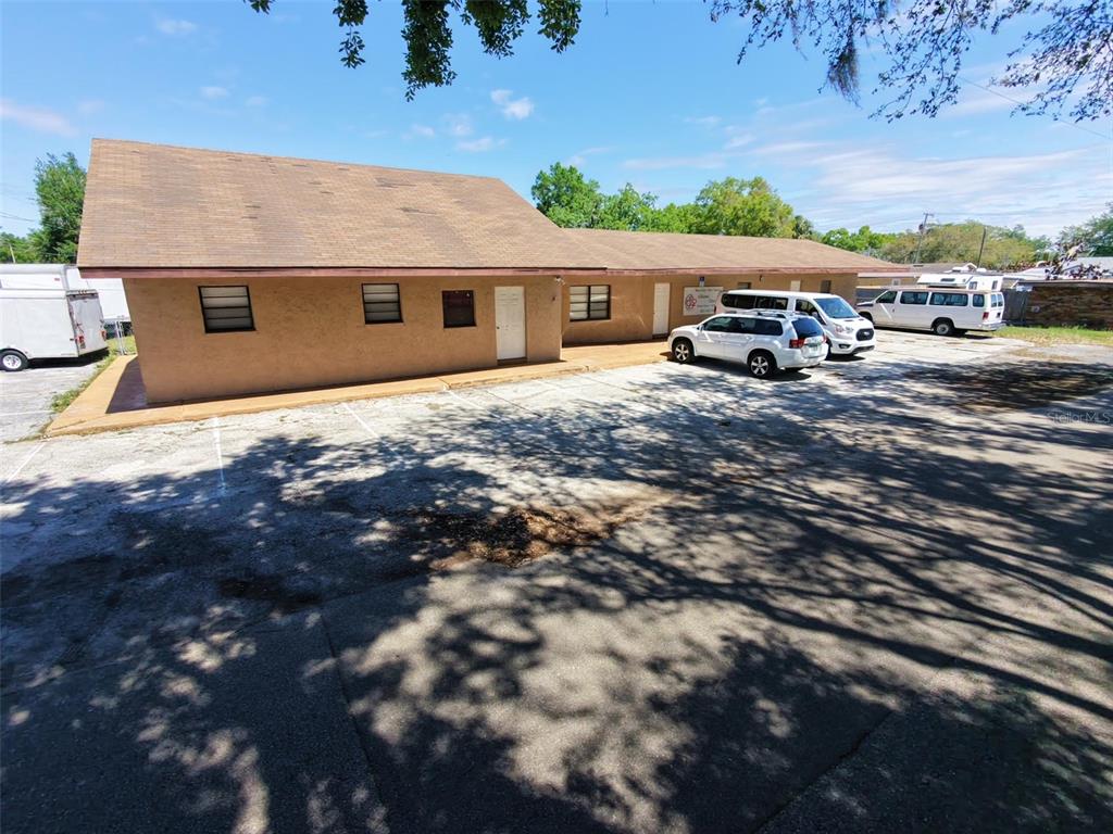 A single-story tan building with a brown roof sits behind a large paved parking lot — 0 MELTON AVENUE, AUBURNDALE, FL