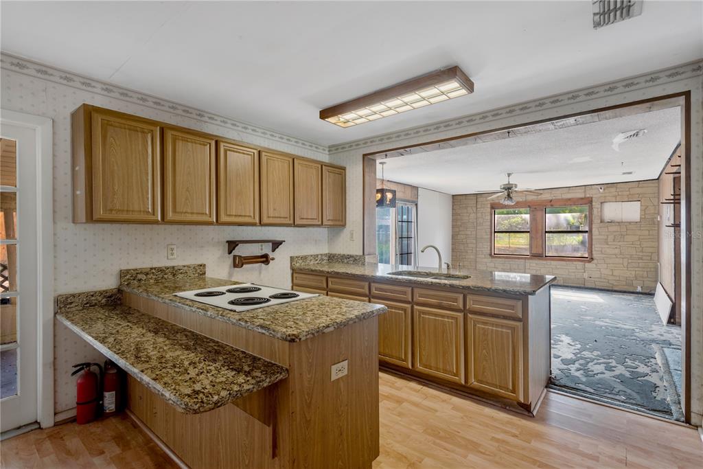 A kitchen with wood cabinets, granite countertops, and a pass-through window to a living area — 418 EUCLID AVENUE, SEFFNER, FL
