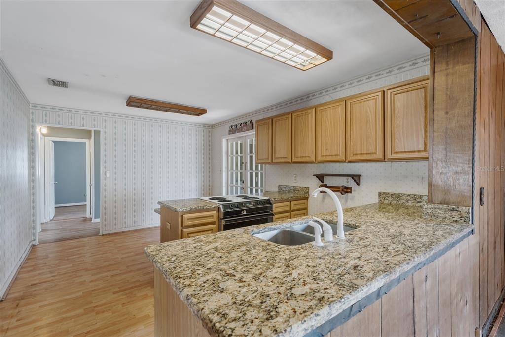 A kitchen features granite countertops, light wood cabinets, and a peninsula with a built-in stove — 418 EUCLID AVENUE, SEFFNER, FL