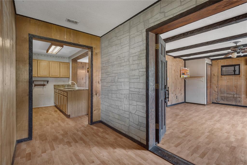 A view through doorways into a kitchen and living area with wood-paneled walls and flooring — 418 EUCLID AVENUE, SEFFNER, FL