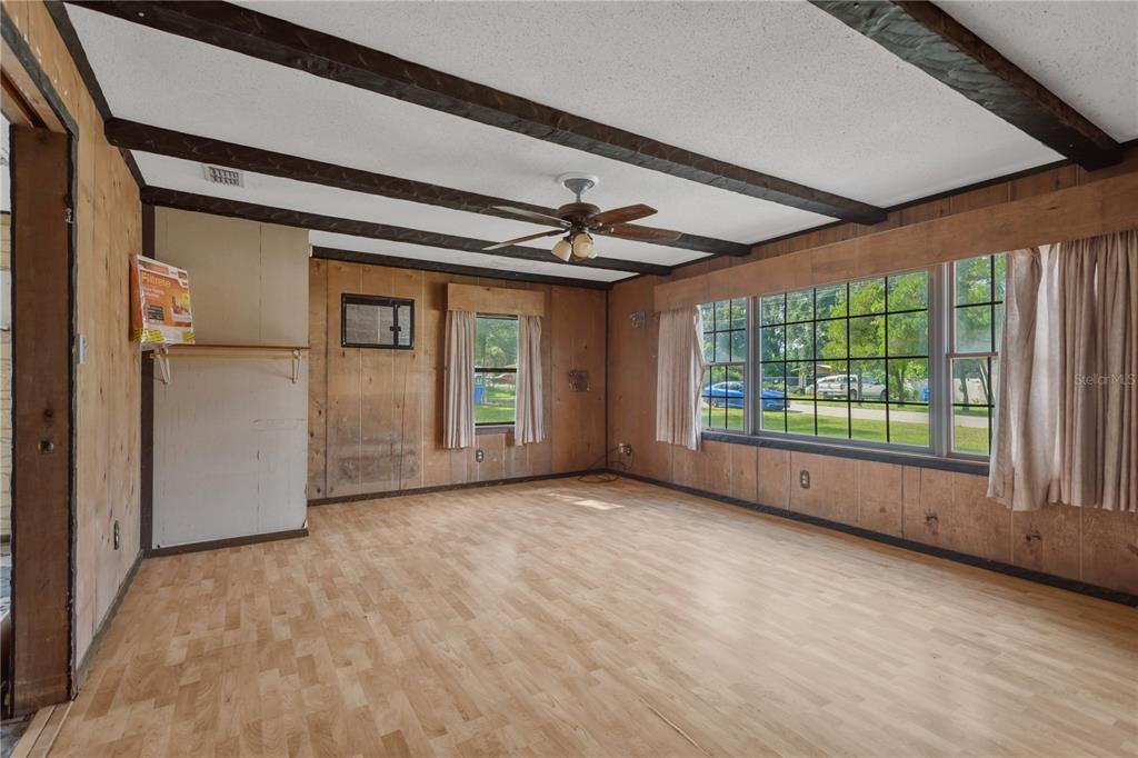 A living room features wood-paneled walls, exposed ceiling beams, a ceiling fan, and large windows — 418 EUCLID AVENUE, SEFFNER, FL