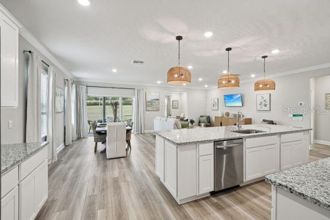 A kitchen with a large granite island and stainless steel appliances opens to a dining area — 6089 CHORUS DRIVE, MASCOTTE, FL
