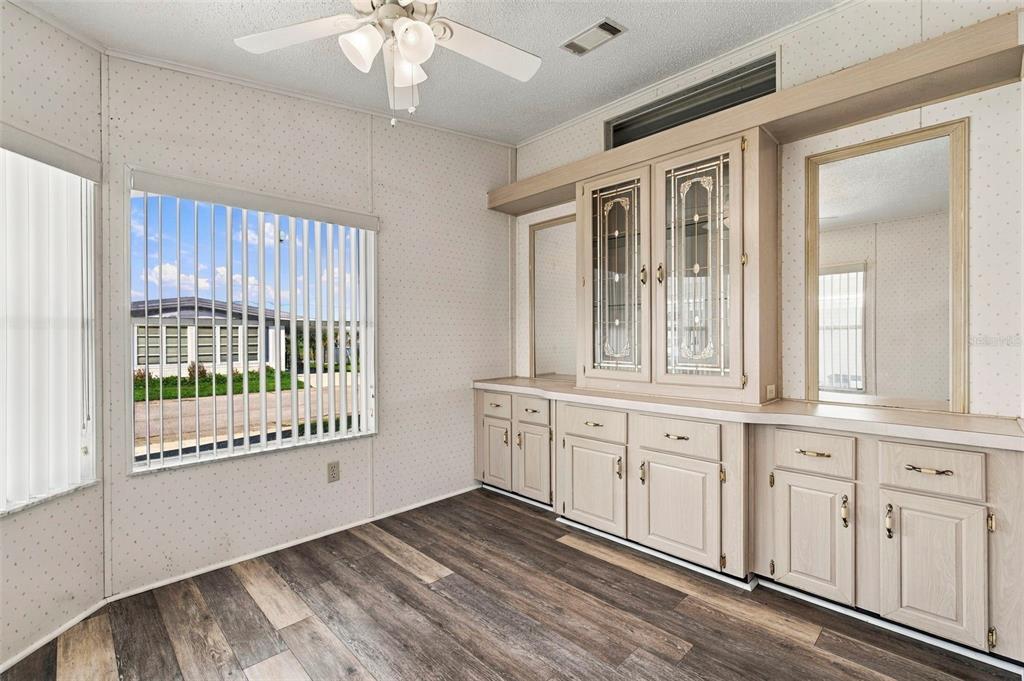A dining room features wood-look flooring, a ceiling fan, vertical blinds, and built-in cabinetry — 340 CANAL WAY, OLDSMAR, FL