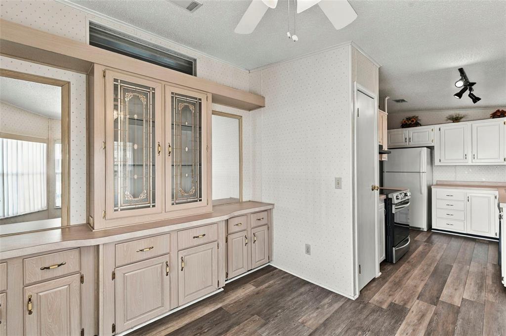 A dining area with a built-in hutch, wood-look flooring, and an adjacent kitchen with white cabinets — 340 CANAL WAY, OLDSMAR, FL