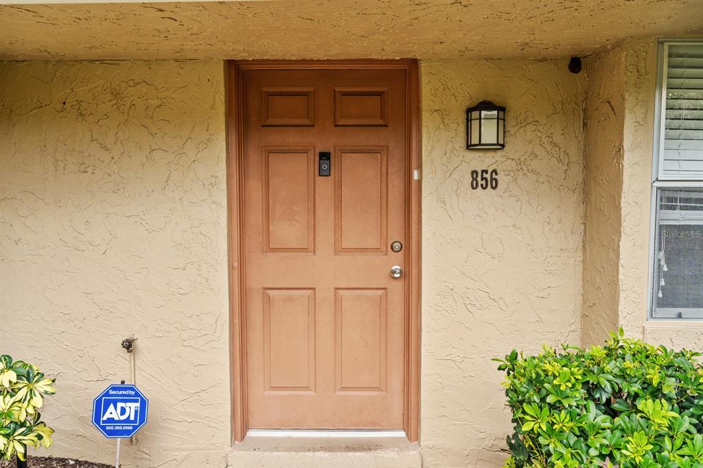 A tan exterior wall features a brown front door with a house number and sign — 856 PARK LAKE CIRCLE UNIT 51, MAITLAND, FL