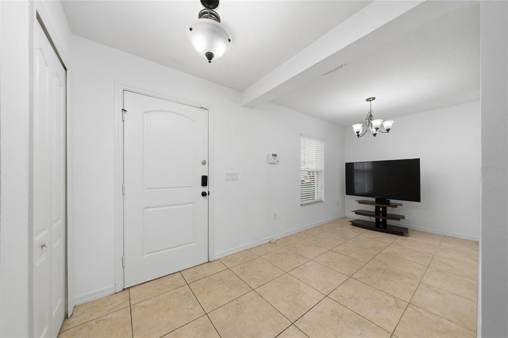 An entryway with tile flooring, a white front door, and a television on a stand — 4752 BLUE DIAMOND STREET, KISSIMMEE, FL