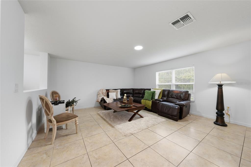 A living room features a dark leather sectional, a wooden coffee table, and tile flooring — 4752 BLUE DIAMOND STREET, KISSIMMEE, FL