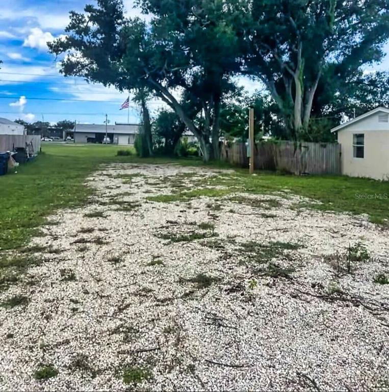 A gravel driveway leads toward a large tree and a wooden fence on a lot — 0 PARK ROAD, VENICE, FL