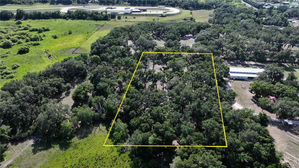 An aerial view shows a wooded lot outlined in yellow near a highway — MUCK POND ROAD, SEFFNER, FL