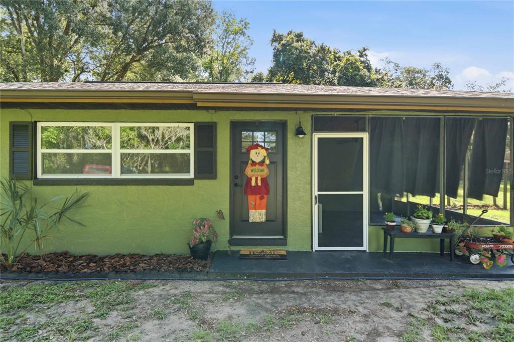 The exterior of a green house features a front door, a window, and a porch — 19791 SE 110TH COURT, INGLIS, FL