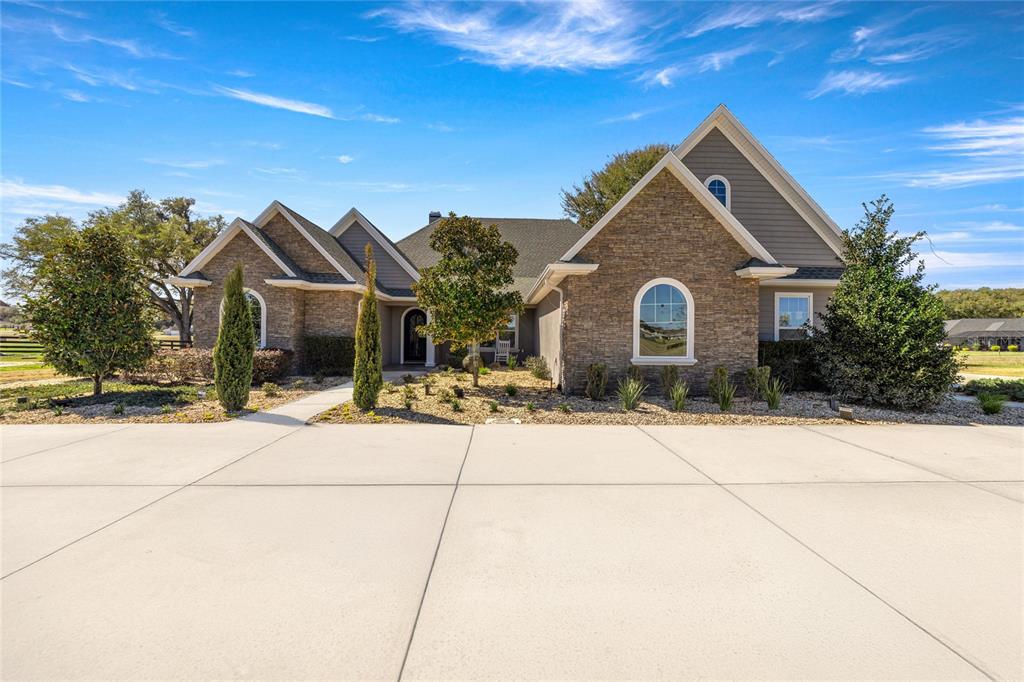 A stone and siding house with an arched window and a large concrete driveway — 1873 NW 85TH LOOP, OCALA, FL