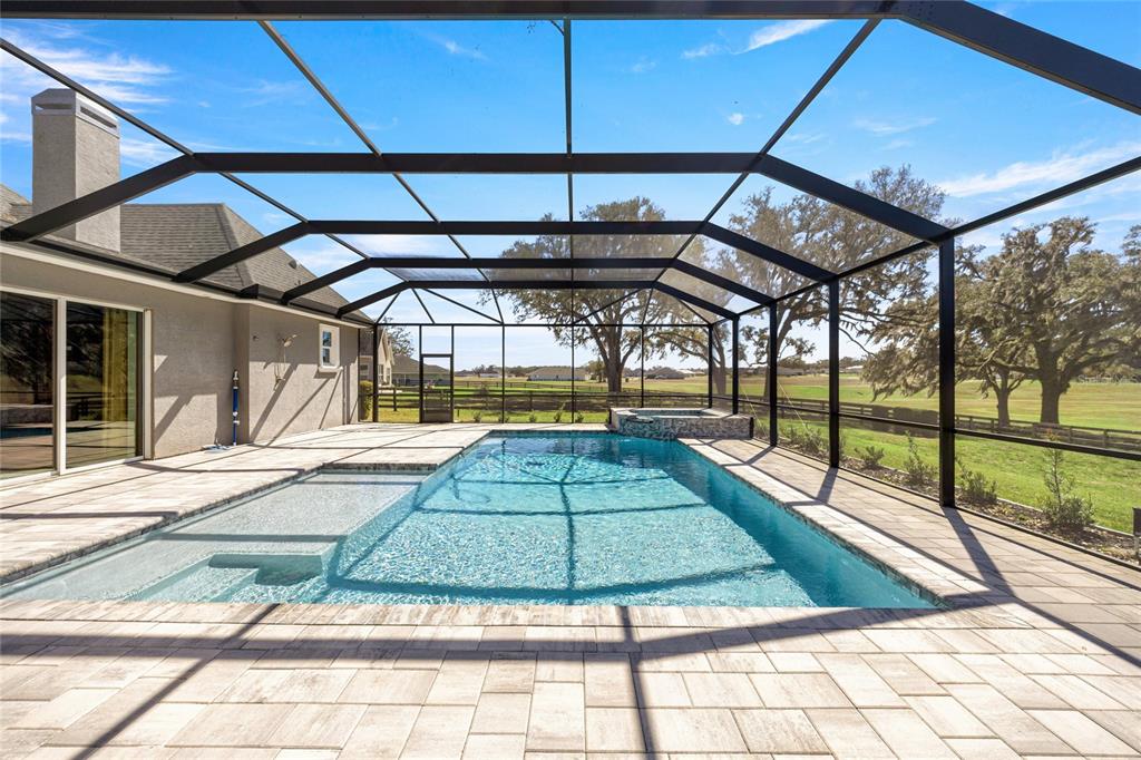 A screened-in patio features a rectangular swimming pool with a tanning ledge and attached spa — 1873 NW 85TH LOOP, OCALA, FL