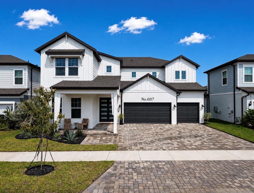 A two-story house with white board-and-batten siding, a dark roof, and a three-car garage — 6117 GOLDEN BEACH DRIVE, APOLLO BEACH, FL