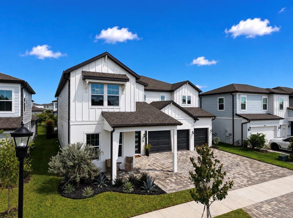 A two-story white house with vertical siding, a paved driveway, and a covered front porch — 6117 GOLDEN BEACH DRIVE, APOLLO BEACH, FL