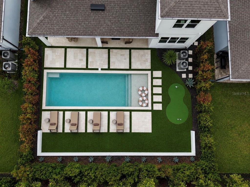 An aerial view of a backyard featuring a rectangular pool, putting green, and lounge area — 6117 GOLDEN BEACH DRIVE, APOLLO BEACH, FL