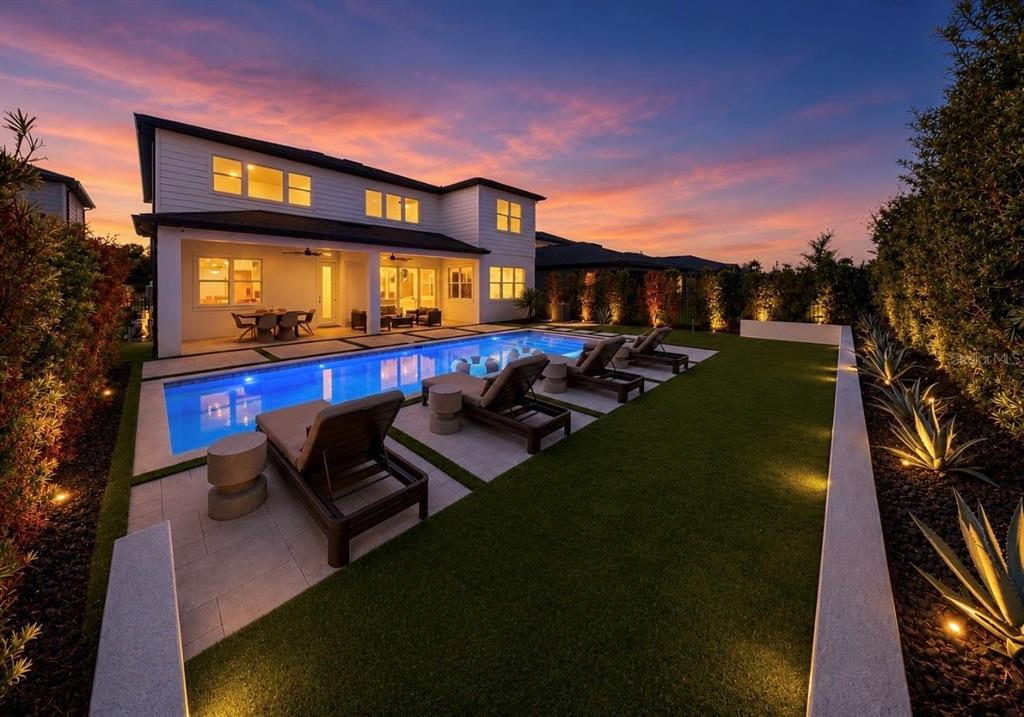 A two-story house with a backyard pool, lounge chairs, and artificial turf at sunset — 6117 GOLDEN BEACH DRIVE, APOLLO BEACH, FL