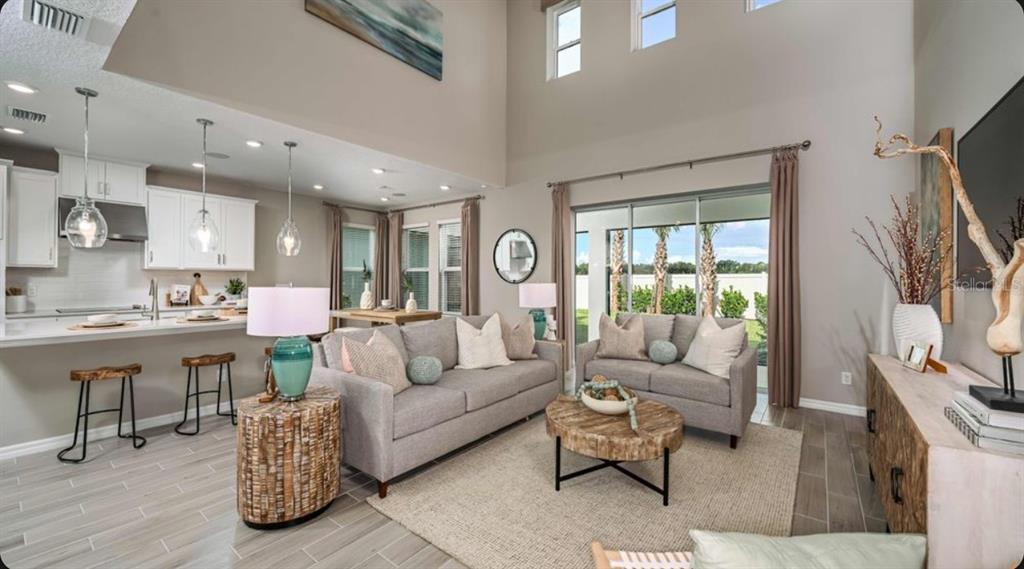 A modern kitchen features white cabinetry, a large island with wooden stools, and pendant lighting — 5770 BINNACLE LANE, COCOA, FL