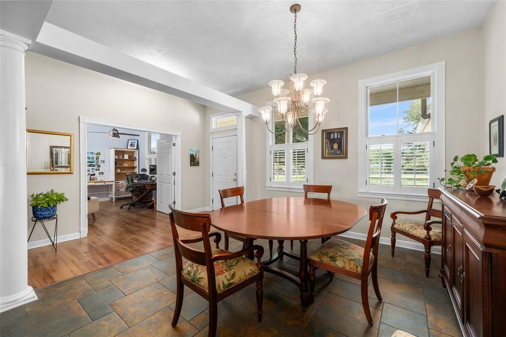 A dining room features a round wooden table, chandelier, tile flooring, and an adjacent office — 12934 NW 173RD LANE, ALACHUA, FL