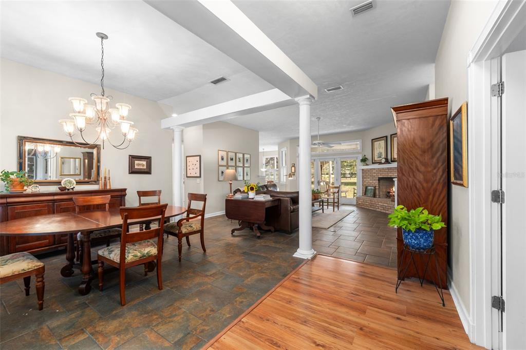 An open-concept living and dining area features tile flooring, a brick fireplace, and white columns — 12934 NW 173RD LANE, ALACHUA, FL