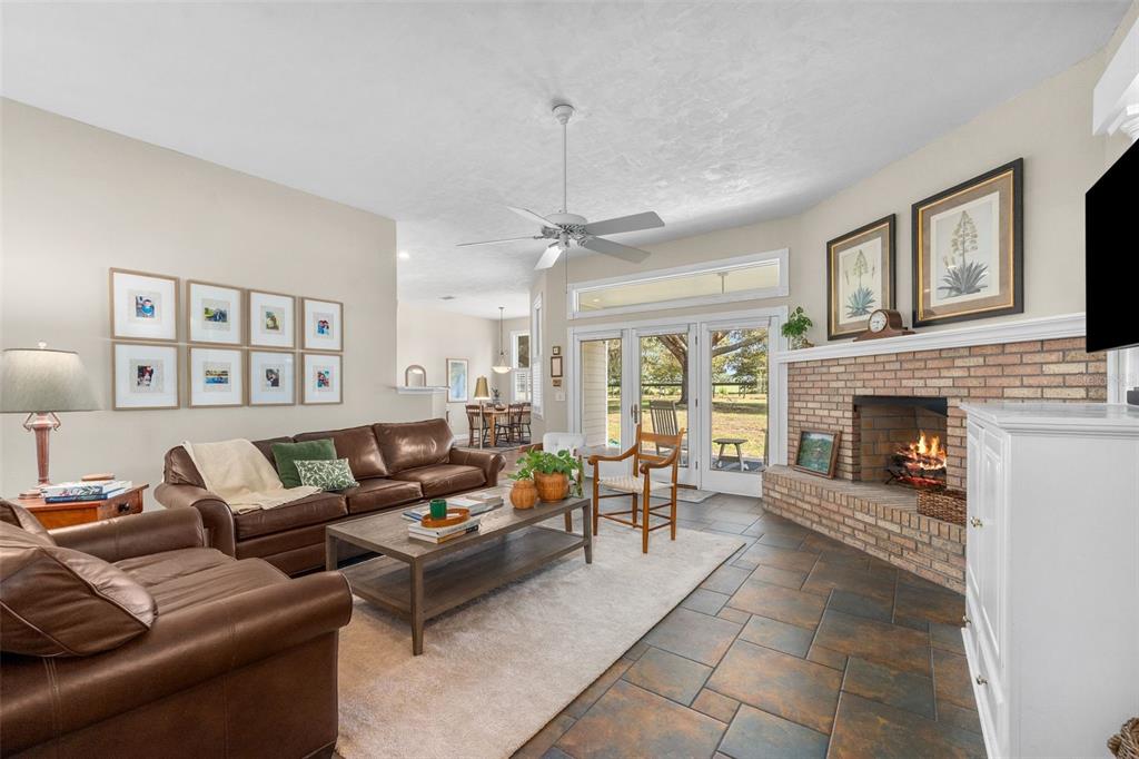 A living room features a brick fireplace, brown leather sofas, tile flooring, and glass doors — 12934 NW 173RD LANE, ALACHUA, FL