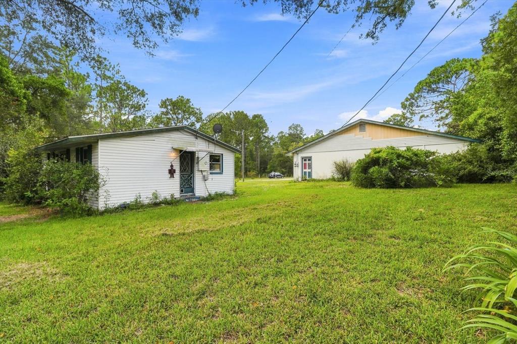 A white house and a separate detached garage sit on a grassy lot with trees — 3750 SW 181ST COURT, DUNNELLON, FL