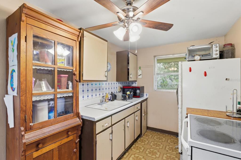 A kitchen features wooden cabinets, a white sink, a ceiling fan, and patterned floor tiles — 3750 SW 181ST COURT, DUNNELLON, FL