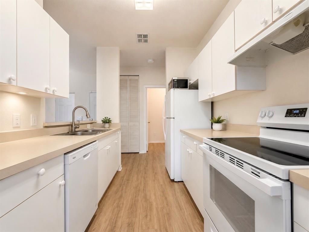 An open-concept living and dining area features light wood-look flooring, gray wainscoting, and a balcony — 3589 CONROY ROAD UNIT 1023, ORLANDO, FL