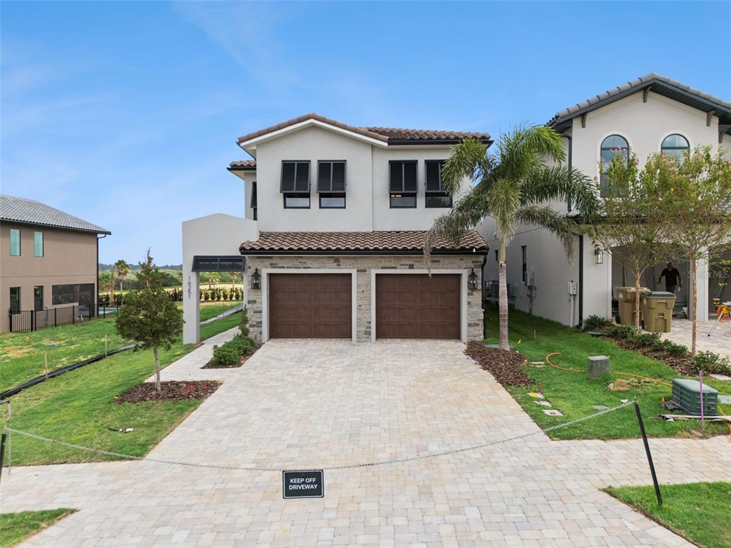 A two-story house with a stucco exterior, stone accents, and a two-car garage — 16251 VETTA DRIVE, BELLA COLLINA, FL