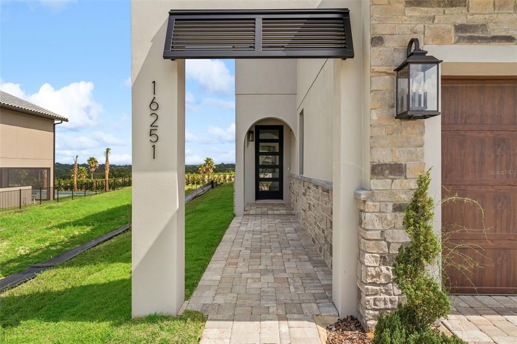An entryway features dark wood floors, a staircase with black railings, and large windows — 16251 VETTA DRIVE, BELLA COLLINA, FL
