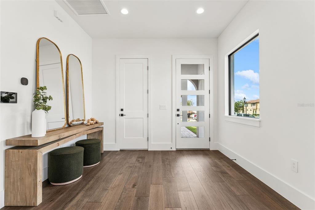 A living room features a stone fireplace, dark wood flooring, and large windows — 16251 VETTA DRIVE, BELLA COLLINA, FL
