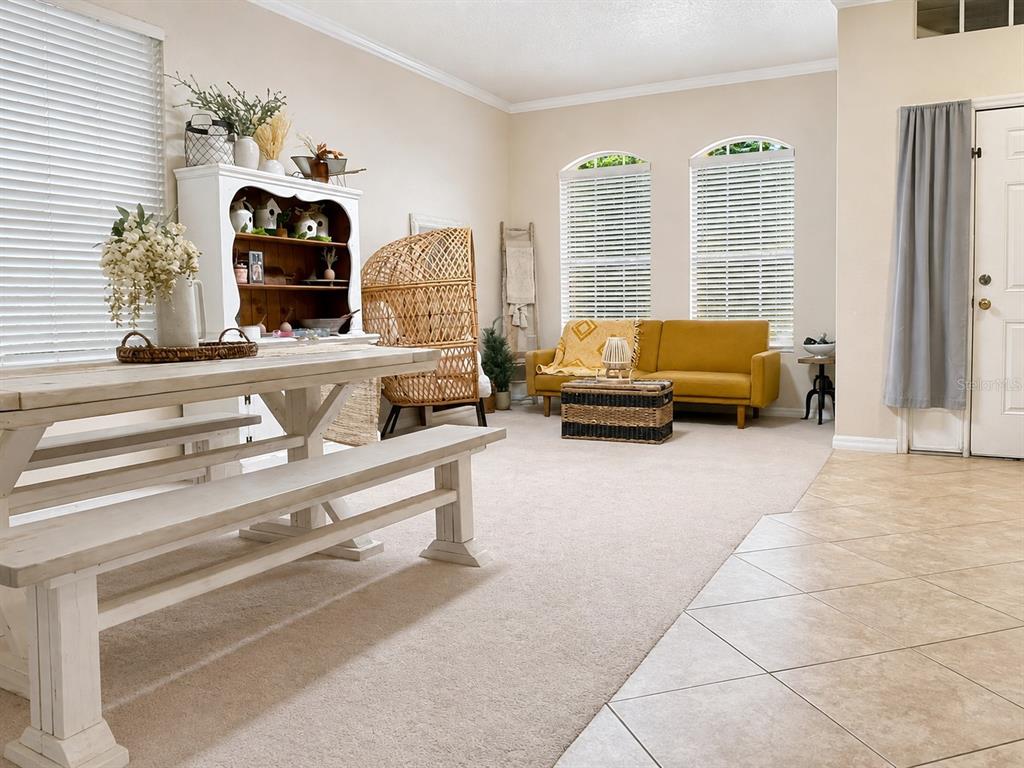 A dining area with a white table and bench sits before a living space with a sofa — 10205 CYPRESS VINE DRIVE, ORLANDO, FL