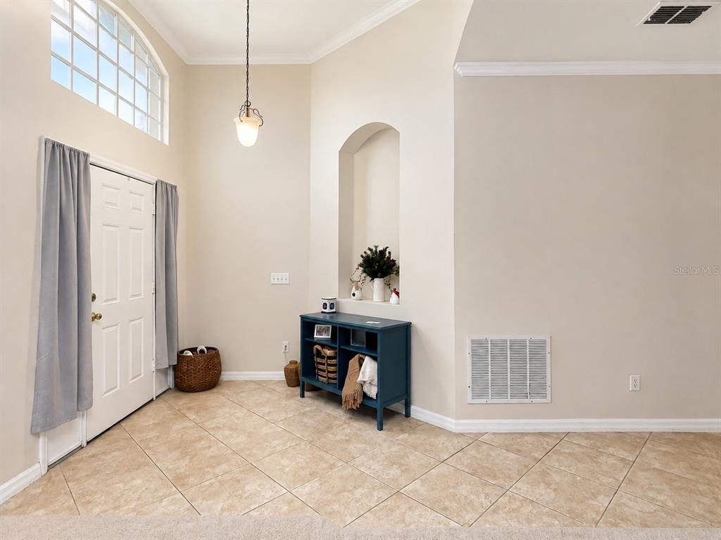 An entryway features tile flooring, a blue console table, a wall niche, and a front door — 10205 CYPRESS VINE DRIVE, ORLANDO, FL