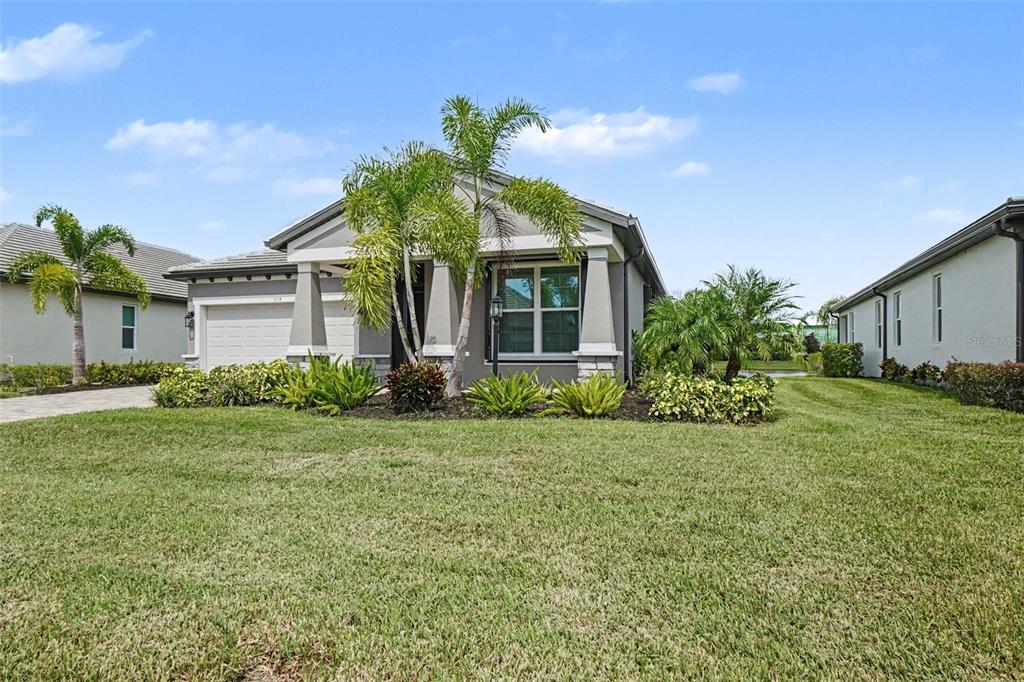 A single-story house with a gray exterior, a two-car garage, and palm trees in front — 3714 WILD BLOSSOM PLACE, PARRISH, FL