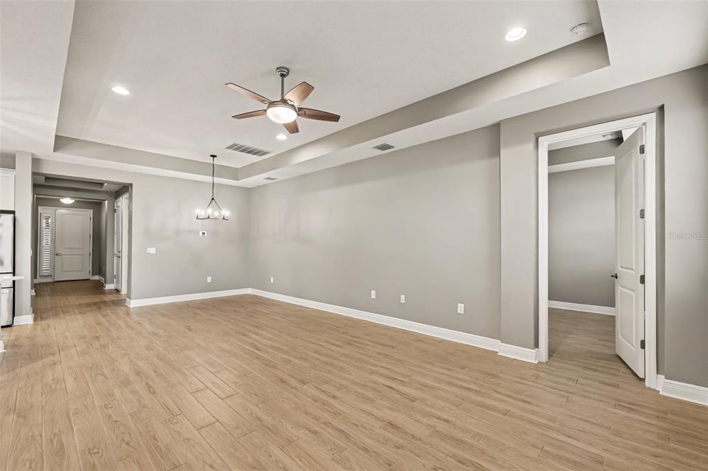 An empty room with light wood-look flooring, gray walls, a tray ceiling, and a ceiling fan — 3714 WILD BLOSSOM PLACE, PARRISH, FL