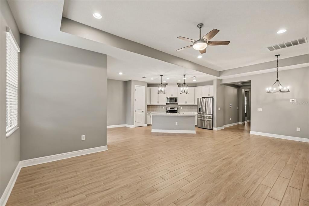 An open-concept kitchen and living area features light wood-look tile flooring and gray walls — 3714 WILD BLOSSOM PLACE, PARRISH, FL