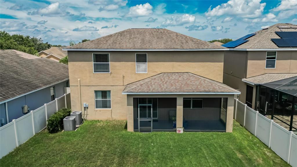 The rear exterior of a two-story house with a screened-in patio and a fenced yard — 8435 HUNTERS FORK LOOP, RUSKIN, FL